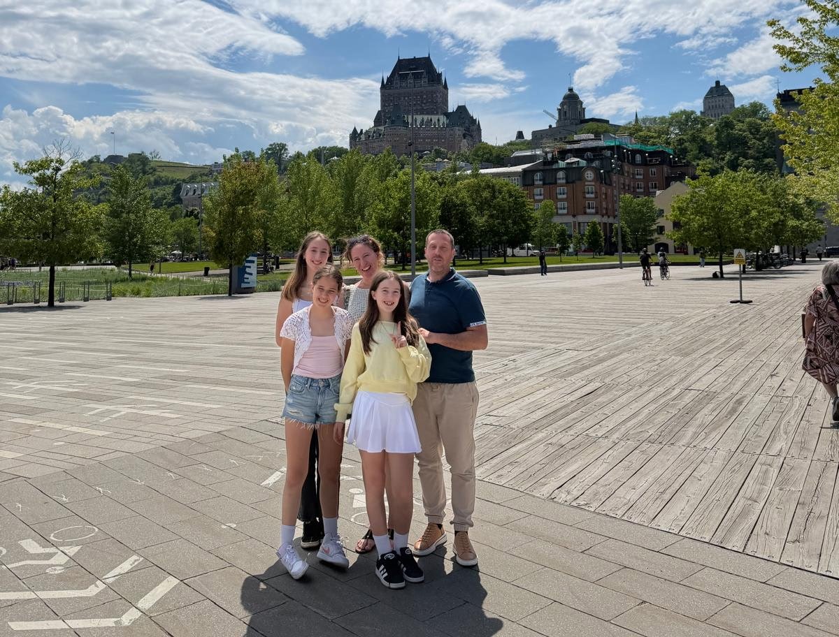 Arnaud, Sabrina and their three daughters on a plaza in Quebec City, with the Chateau Frontenac behind them