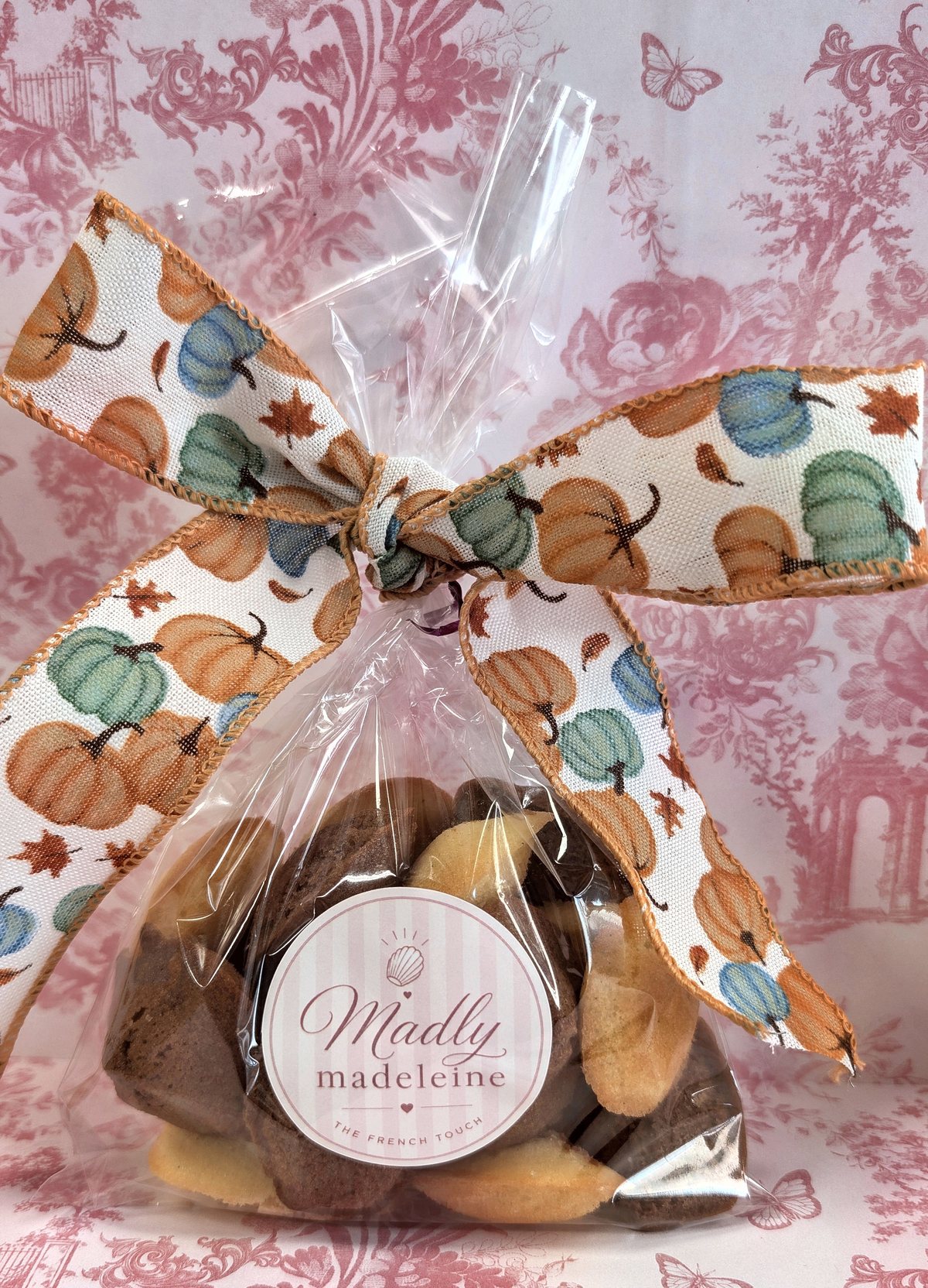 A cellophane gift bag of madeleines tied with an autumn pumpkin ribbon and the Madly Madeleine sticker
