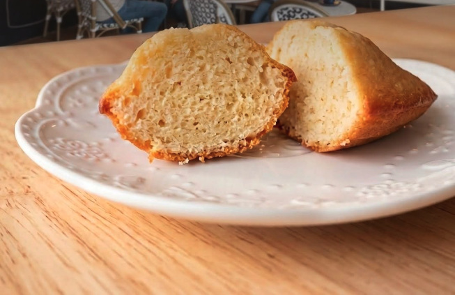 A madeleine cut in half to show its soft golden interior